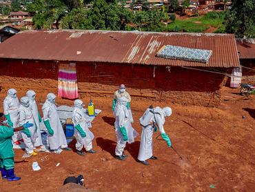 A vöröskereszt munkatársai, egy ebolában elhunyt beteg háza környékét fertőtlenítik 2026. május 24-én