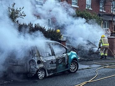 Firefighters work to extinguish a fire in three cars parked on the street at Tigers Bay, during a protest after a knife attack on June 8 left a man seriously injured and prompted police to declare a critical incident, in Belfast, Northern Ireland, June 9, 2026. REUTERS/Isabel Infantes