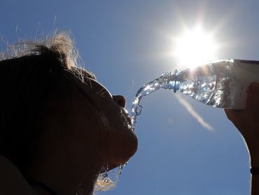 26 July 2018, Germany, Berlin: With temperatures around 33 degrees Celsius, a young woman drinks sparkling water for refreshment. According to the meteorologists, temperatures will rise well above 30 degrees in the coming days. Photo: Wolfgang Kumm/dpa (Photo by Wolfgang Kumm/picture alliance via Getty Images)