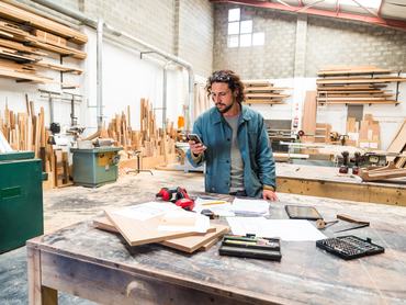 Fiatal férfi asztalos a műhelyében dolgozik