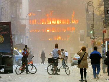 394261 111: People walk in the street in the area where the World Trade Center buildings collapsed September 11, 2001 after two airplanes slammed into the twin towers in a suspected terrorist attack. (Photo by Mario Tama/Getty Images)