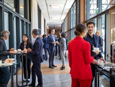 Business people having a refreshment break at conference. Corporate professionals standing in corridor and having coffee.