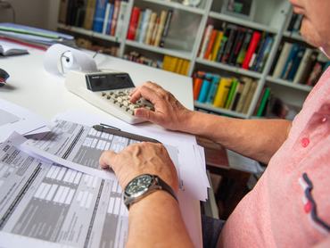 29 May 2021, North Rhine-Westphalia, Bad Oeynhausen: ILLUSTRATION - A pensioner fills out his tax return and types numbers into a desk calculator to calculate it. The Federal Fiscal Court will announce rulings in two cases on pension taxation on Momtag (31.05.2021). The issue is whether the federal government is wrongly taxing pensions twice. (to "Federal Fiscal Court announces pension rulings - major effects possible") Photo: Lino Mirgeler/dpa (Photo by Lino Mirgeler/picture alliance via Getty Images)