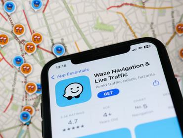 Waze on App Store displayed on a phone screen and map on Waze website displayed on a screen in the background are seen in this illustration photo taken in Krakow, Poland on January 19, 2023. (Photo by Jakub Porzycki/NurPhoto via Getty Images)