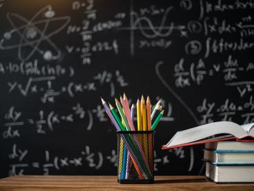 Back to school supplies. Books and blackboard on wooden background