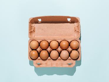 Organic eggs in cartons tray on blue background. Flat lay, top view