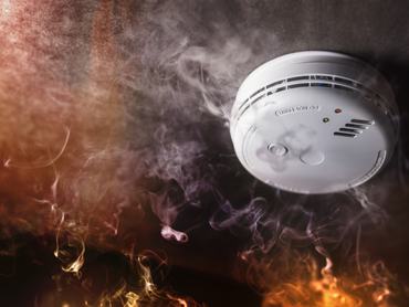 Smoke detector and fire alarm in action background with copy space