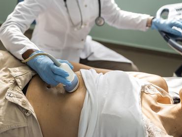 Doctor examining mature woman with ultrasound scanner device