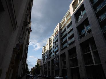 Urban street scene featuring modern high-rise buildings with a dramatic sky backdrop. Captures the architecture and atmosphere of city life.