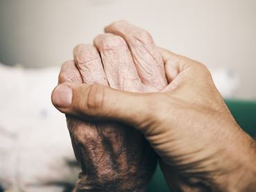A man holding hands with a 90 year old senior man.