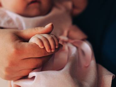 A close-up of a mother gently holding her baby's tiny hand, symbolizing love, care, and the precious bond of family. The soft tones and delicate details create a warm and emotional image, ideal for themes related to motherhood, parenting, and family values.