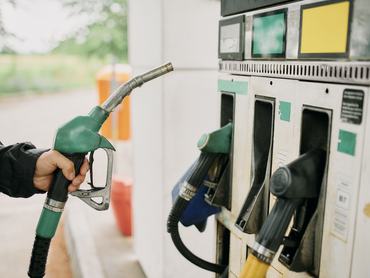 Hand, person or gas station with fuel gun, machine and transport cost for energy, pistol or petrol service. Closeup, gasoline or motor vehicle maintenance at garage to pump tank on road trip travel