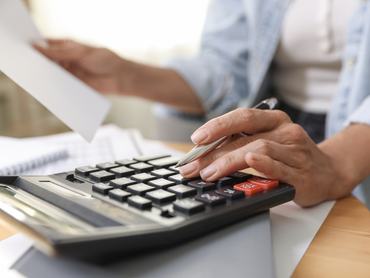 Budget planning. Woman using calculator while working with accounting document at table indoors, closeup