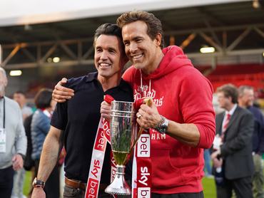 WREXHAM, WALES - APRIL 26: Rob McElhenney and Ryan Reynolds, co-owners of Wrexham AFC, pose for a photo with the trophy following the club's promotion to the Sky Bet Championship during the Sky Bet League One match between Wrexham AFC and Charlton Athletic FC at Racecourse Ground on April 26, 2025 in Wrexham, Wales. (Photo by Kya Banasko/Getty Images)