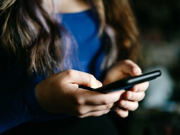 A focused view of individual's hands using a mobile phone indoors, conveying technology and communication concepts.