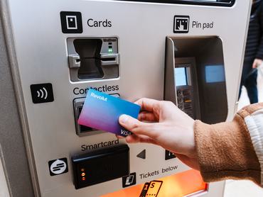 London, United Kingdom - 14 March, 2025: Person tapping Revolut Visa bank card on contactless payment terminal of ticket vending machine in urban transport station, Transportation services, Digital payment