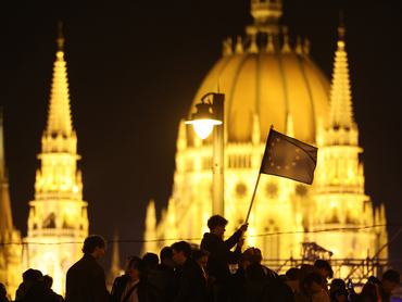 BUDAPEST, HUNGARY - APRIL 12: Revellers, including one waving the flag of the European Union, celebrate the resounding Tisza party win in Hungarian parliamentary elections as Hungary's parliament building stand illuminated behind on April 12, 2026 in Budapest, Hungary. Prime Minister Viktor Orban of the Fidesz party has conceded his party's election loss, paving the way for Peter Magyar, lead candidate of the Tisza party, to become the next prime minister.  (Photo by Sean Gallup/Getty Images)