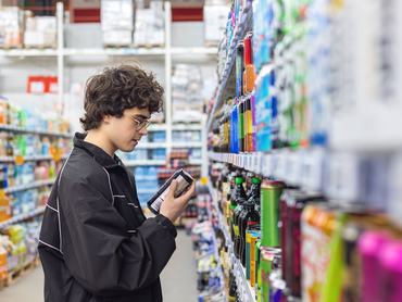 Adolsent boy reading beverage label while shopping in supermarket.  unhealthy beverage habits and health risk