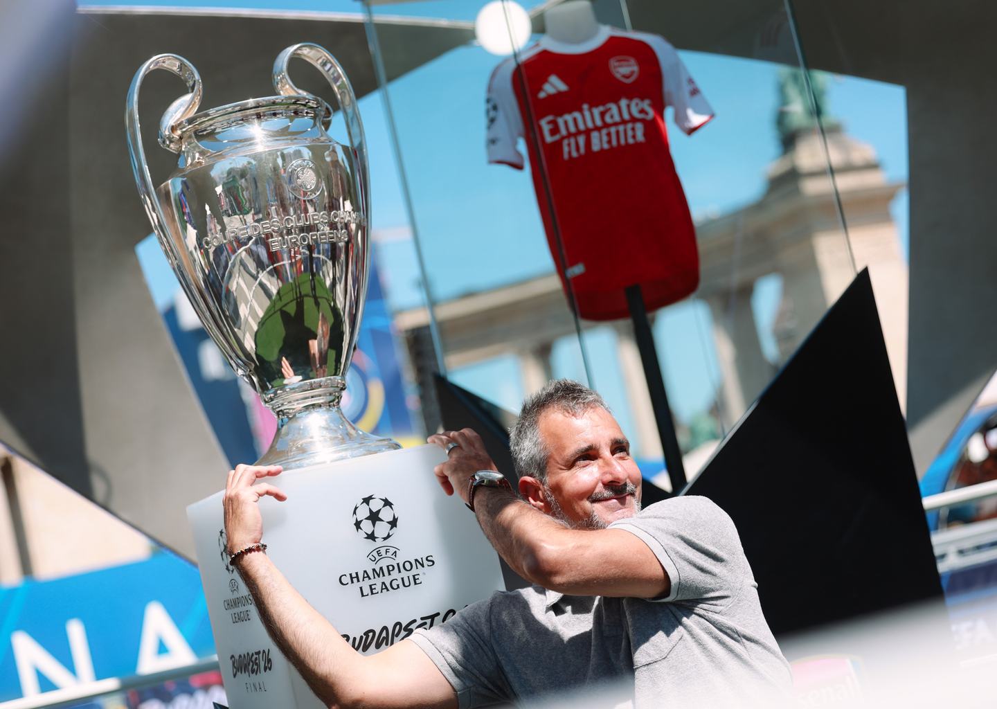 Egy szurkoló pózol a Bajnokok Ligája trófeájával a budapesti Hősök terén 2026. május 28-án
