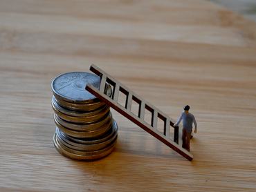 Tower of forint coins with elderly figure standing at the ladder base, symbolizing financial struggle, inflation, and vulnerability in old age.