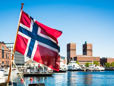 Norwegian flag in front of the city hall building in Oslo, Norway capital city during a sunny summer day.