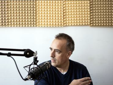 Török Gábor egy mikrofonba beszél egy podcast felvétele alatt