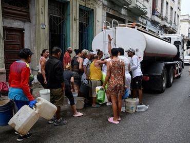 People gather around a water tanker truck to fill up buckets and other containers as severe fuel shortages have disrupted water pumping and distribution, in Havana, Cuba March 19, 2026. REUTERS/Norlys Perez      TPX IMAGES OF THE DAY