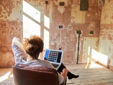 Mature woman sitting in her kitchen at home thinking about new wall colours for her renovation project.
