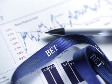 Grafikonok egy papírlapon és a Budapest Értektőzsde felirat egy nyakpánton