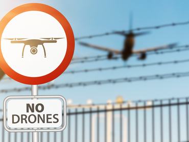 close-up of drone prohobition sign against security fence and airplane landing on airport