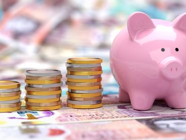 Piggy Bank with stacks of coins on British pound banknotes