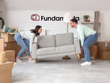 Happy young couple carrying sofa in room on moving day