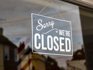 Closed sign hanging in the window of a small shop